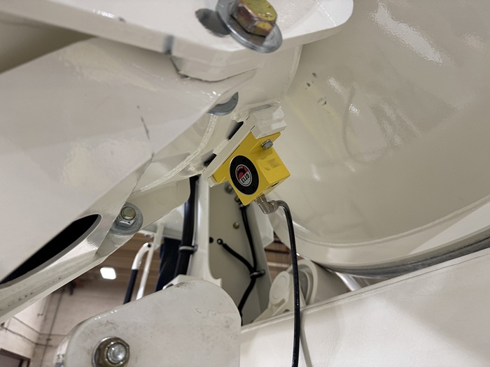 A yellow GT13 chute vibrator attached to the underside of an INTEGRALdx concrete redi-mix truck chute.