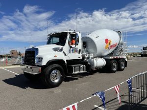 The front left side of a conventional-styled INTEGRALdx concrete redi-mix truck built for TransCHICAGO, who represented us at the National Ready Mixed Concrete Association's annual tournament. An INTEGRALdx logo is visible along the drum. It has a Freightliner chassis.