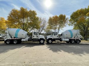 The side views of two conventional INTEGRALdx concrete redi-mix trucks. They both have single blue stripes wrapped around the drum, the signature look of River Road.