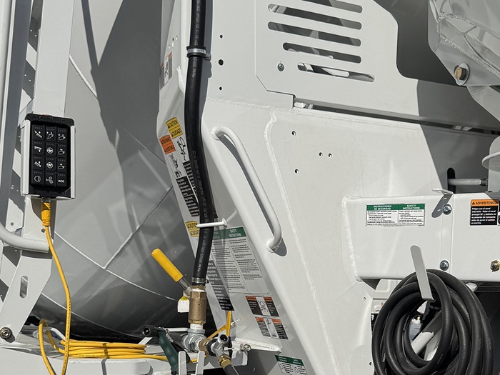 A grab handle on the back left side of an INTEGRALdx concrete redi-mix truck, just ahead of a deadman valve and rear controls.