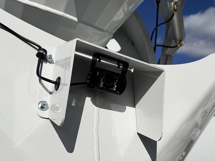 A closeup of a black protected backup camera on an INTEGRALdx concrete redi-mix truck, with a protective white cover over it.