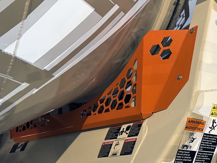 A view of an INTEGRALdx concrete redi-mix truck's orange front roller guard, meant to prevent appendages from getting caught in the drum rollers.